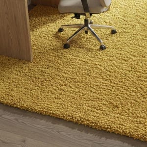 Mustard hand-tufted shag rug in a modern living room; soft yellow solid-color wool rug on light wood floor.