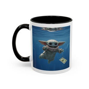 May include: White ceramic mug with a black handle and interior. The mug features a colorful graphic of a character from a popular science fiction series underwater, holding a dollar bill. The background is blue.