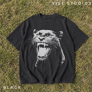May include: A black short-sleeve t-shirt featuring a large white graphic print of a snarling panther head with its mouth open. The text VISE STUDIOS is printed in white in the top right corner, and the word BLACK is in the bottom left corner.
