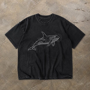 May include: A black short-sleeve t-shirt featuring a white line art graphic of an orca whale. The design depicts the whale in a technical, schematic style with thin white lines outlining its body and circular sonar patterns near the head.