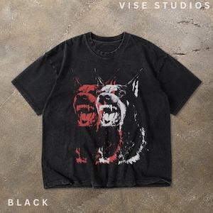 May include: A black short-sleeve t-shirt featuring a graphic print of a snarling Doberman dog in red and white. The design has a layered, offset effect. The text VISE STUDIOS is printed in the top right corner and the word BLACK is in the bottom left.