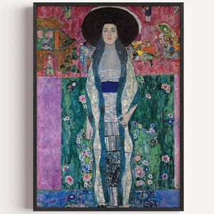 May include: A framed art print featuring a portrait of a person wearing a large black hat, a light-coloured high-neck garment, and a long patterned coat with blue accents. The background displays a vibrant, abstract composition of pink, green, and floral motifs.