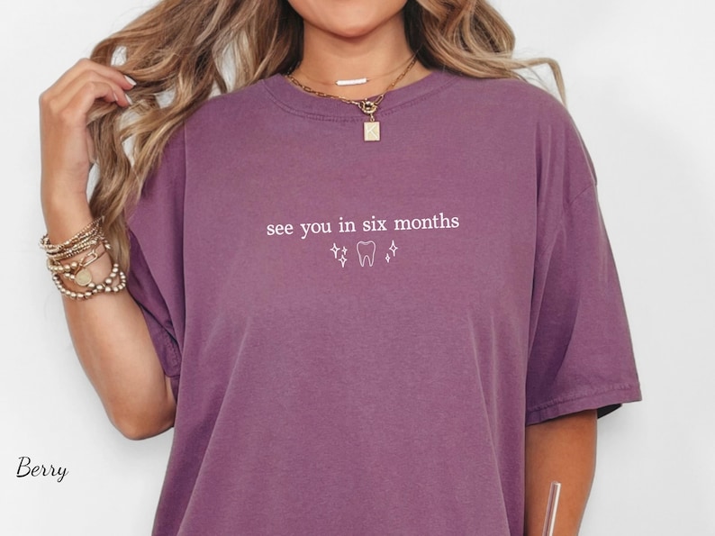 K&ouml;nnte beinhalten: Beerenfarbenes T-Shirt mit dem Text "see you in six months" und einer Zahn-Grafik. Das Shirt hat kurze &Auml;rmel und einen Rundhalsausschnitt. Das Shirt ist einfarbig und hat eine lockere Passform.