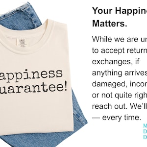 Puede incluir: Camiseta color crema con el texto "Happiness Guarantee!" en negro, sobre mezclilla azul. La camiseta tiene cuello redondo y una etiqueta peque&ntilde;a. La imagen tambi&eacute;n incluye texto sobre la satisfacci&oacute;n del cliente.