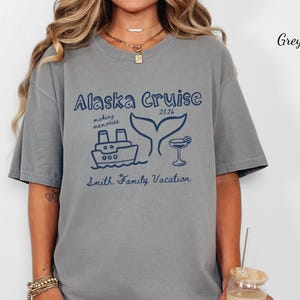 May include: Grey t-shirt with a navy blue graphic that reads "Alaska Cruise 2026" with a ship, whale tail, and cocktail illustration. The text "making memories" and "Smith Family Vacation" are also included.