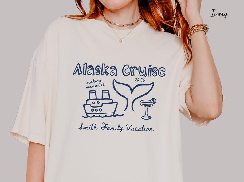 May include: Ivory-colored t-shirt with a navy blue graphic that reads "Alaska Cruise 2026". The design includes a ship, whale tail, and cocktail. The text "making memories" and "Smith Family Vacation" are also included.