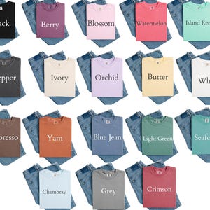 K&ouml;nnte beinhalten: Eine Auswahl an T-Shirts in verschiedenen Farben, darunter Schwarz, Beere, Bl&uuml;te, Wassermelone und Inselriff, jeweils kombiniert mit einer gefalteten Jeans. Die Shirts sind mit ihren jeweiligen Farbbezeichnungen versehen.