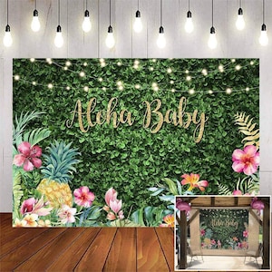 May include: A tropical-themed backdrop with the text "Aloha Baby" in gold glitter. The backdrop features lush green foliage, pink hibiscus flowers, a pineapple, and string lights, perfect for a baby shower or party.
