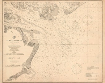May include: A vintage nautical chart of St. Helena Sound, South Carolina. The chart shows the depth of the water in feet and the location of various landmarks. The chart is printed on a cream-colored paper with a compass rose in the bottom right corner.