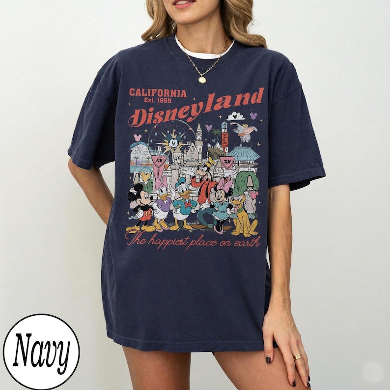 May include: Navy blue t-shirt with a Disneyland graphic. The design includes the text "CALIFORNIA Est. 1955 Disneyland" and "The happiest place on earth" with cartoon characters and park landmarks.