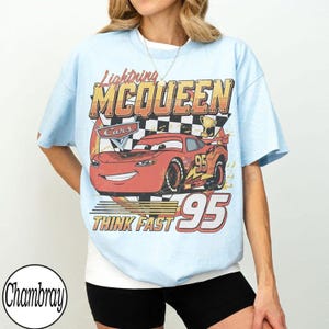 May include: Light blue t-shirt featuring Lightning McQueen from the Cars movie. The graphic includes McQueen's image, the number 95, and the text "THINK FAST". The shirt has a crew neck and short sleeves.