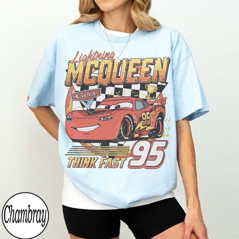 May include: Light blue t-shirt featuring Lightning McQueen from the Cars movie. The graphic includes McQueen's image, the number 95, and the text "THINK FAST". The shirt has a crew neck and short sleeves.