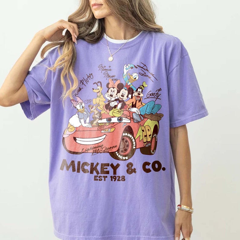 Może przedstawiać: Liliowa koszulka z grafiką Myszki Miki i przyjaci&oacute;ł w czerwonym samochodzie. Samoch&oacute;d ma napis "Lightning McQueen". Na koszulce widnieje r&oacute;wnież napis "Mickey & Co. EST 1928".