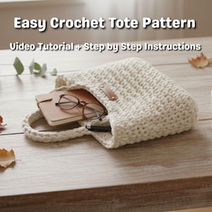 May include: Cream-colored crochet tote bag with a handle, containing a notebook, glasses, and a pen. The bag has a leather tag. Text on the image reads "Easy Crochet Tote Pattern" and "Video Tutorial + Step by Step Instructions."