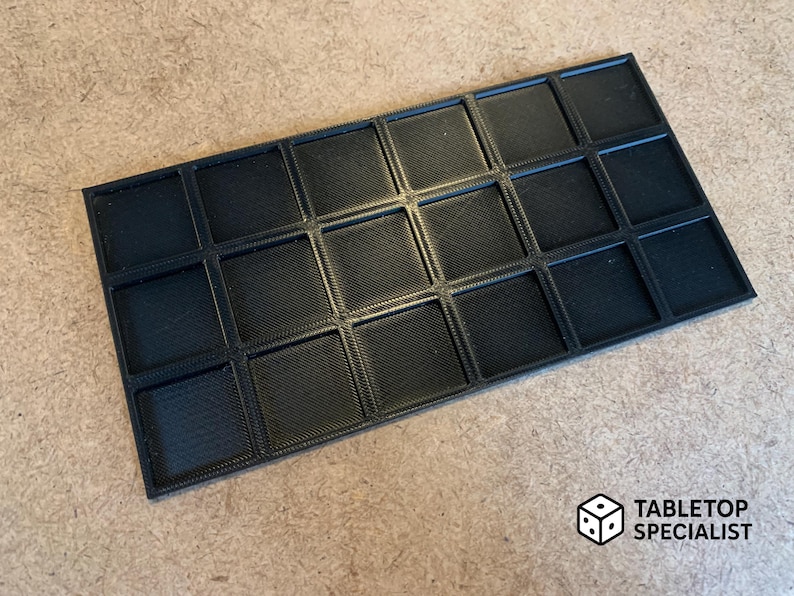 Op de afbeelding: Een zwart, rechthoekig dienblad met 20 vierkante compartimenten. De lade heeft een gestructureerd oppervlak en is ontworpen voor het organiseren van kleine items. Het logo "TABLETOP SPECIALIST" staat rechtsonder.