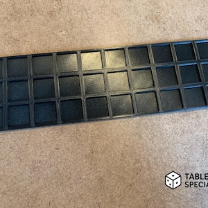 Op de afbeelding: Een zwart, rechthoekig dienblad met 30 vierkante vakken. De lade is gemaakt van een materiaal met textuur en is ontworpen om kleine items in te bewaren. Het Tabletop Specialist-logo staat rechtsonder.