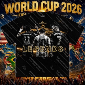May include: A black t-shirt featuring a graphic of soccer players Neymar Jr, Messi, and Ronaldo from the back. The text reads WORLD CUP 2026, FIFA WORLD CUP SINCE 1930, and LEGENDS. The design includes a stadium background and soccer balls.