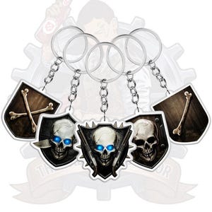 Pode incluir: Um conjunto de cinco porta-chaves com designs em forma de escudo, argolas e correntes metálicas. Os designs incluem crânios com olhos azuis brilhantes, ossos cruzados e ossos individuais sobre fundos escuros e texturizados.