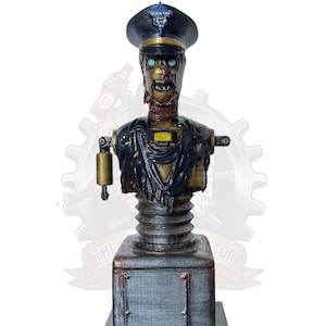 Peut inclure: Buste détaillé d'un policier zombie, avec un chapeau bleu foncé, des traits du visage en décomposition et un corps métallique. La figurine est montée sur une base rectangulaire avec une finition argentée, mettant en valeur une esthétique steampunk.