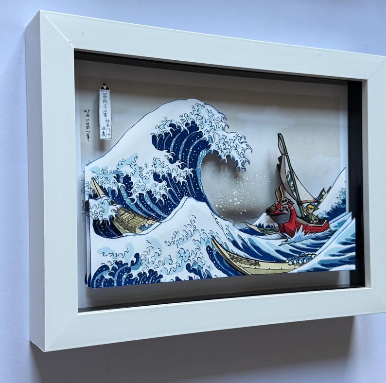 Pode incluir: Obra de arte emoldurada retratando uma onda oce&acirc;nica estilizada com barcos. A onda &eacute; renderizada em tons de azul e branco, com barcos amarelos e vermelhos. A obra de arte est&aacute; em uma moldura branca.