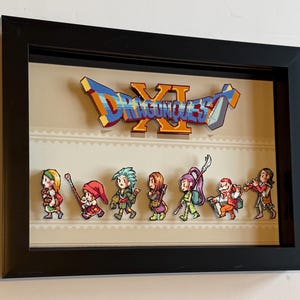 Pode incluir: Obra de arte emoldurada com o logotipo "Dragon Quest XI" e figuras de personagens pixelizados. Os personagens estão dispostos abaixo do logotipo, sobre um fundo bege com uma borda decorativa, dentro de uma moldura preta.