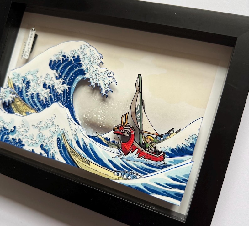 Pode incluir: Obra de arte emoldurada retratando um barco vermelho com um personagem navegando por uma grande onda oce&acirc;nica. A onda &eacute; azul e branca, ao estilo da arte tradicional japonesa. A moldura &eacute; preta.