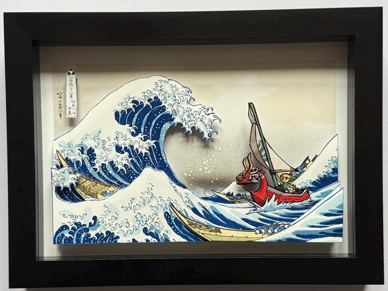 Pode incluir: Obra de arte emoldurada retratando uma cena oce&acirc;nica estilizada com uma grande onda azul e barcos. A obra apresenta um barco vermelho com um personagem e uma est&eacute;tica de estilo japon&ecirc;s. A moldura &eacute; preta.