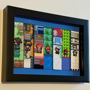 May include: Framed pixel art featuring various characters and scenes from a video game. The artwork is divided into vertical strips, each depicting a different environment or location. The frame is black, and the background is blue.