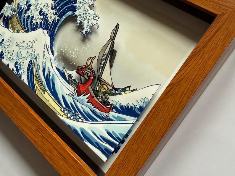 Pode incluir: Obra de arte emoldurada retratando uma cena de ondas japonesas estilizadas com um barco. O barco apresenta uma figura de proa de drag&atilde;o vermelho e um personagem de videogame. A obra de arte est&aacute; em uma moldura de madeira.