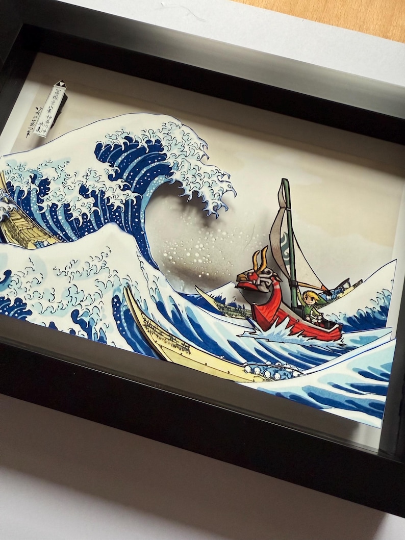 Pode incluir: Uma obra de arte 3D emoldurada que retrata uma onda oce&acirc;nica estilizada com um barco e personagens. A onda &eacute; renderizada em tons de azul e branco, com um barco e personagens na crista. A obra de arte &eacute; emoldurada em uma moldura preta.