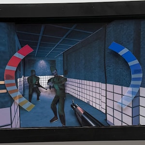 May include: Framed artwork featuring a scene from a video game. The artwork depicts figures in green uniforms holding weapons in a blue-toned corridor. Semi-circular, multi-colored accents are placed on the left and right sides of the image.