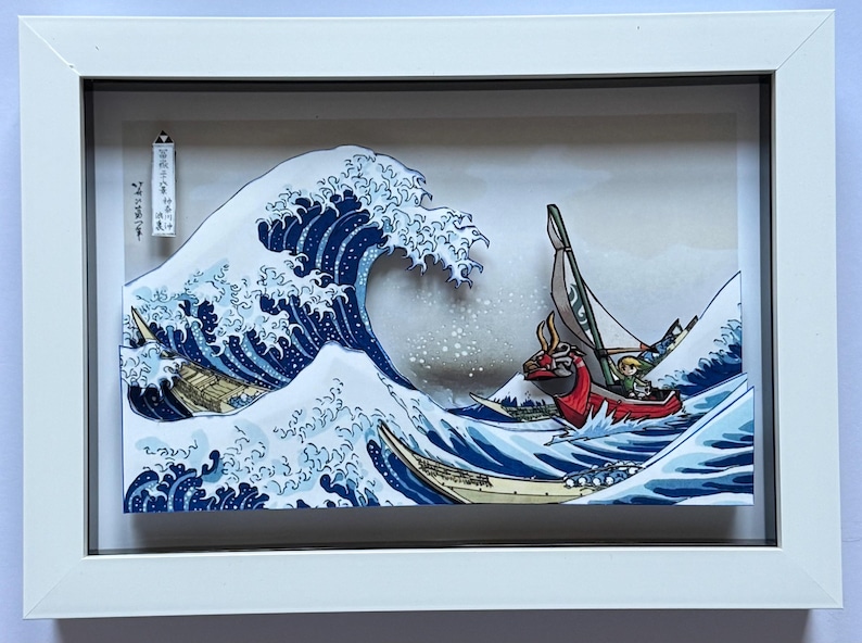 Pode incluir: Obra de arte emoldurada retratando uma cena oce&acirc;nica estilizada com uma grande onda azul e v&aacute;rios barcos. A obra apresenta um barco vermelho com um personagem e uma est&eacute;tica de estilo japon&ecirc;s. A moldura &eacute; branca.
