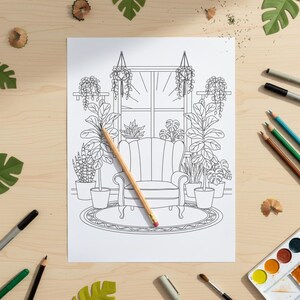 Op de afbeelding: Zwart-wit lijntekening van een gezellige binnensc&egrave;ne met een raam, fauteuil en potplanten. Een potlood ligt op de pagina, omringd door kunstbenodigdheden en decoratieve bladeren, wat duidt op een kleurboek of kunstproject.