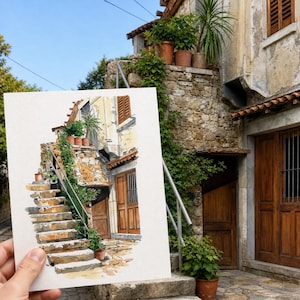 Peut inclure: Une aquarelle d'un bâtiment en pierre avec des escaliers et des plantes en pot. L'œuvre représente une scène architecturale détaillée avec une porte et une fenêtre en bois, et une rampe métallique. La peinture est tenue devant le bâtiment réel, créant une comparaison visuelle.
