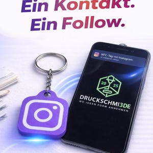 Könnte beinhalten: Ein lila Instagram-Logo-Schlüsselanhänger mit einem silbernen Schlüsselring neben einem Smartphone, das ein Logo und den Text "DRUCKSCHMI3DE" anzeigt. Das Telefon zeigt "NFC-Tag von Instagram". Text lautet "Ein Tipp. Ein Kontakt. Ein Follow."