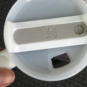 Puede incluir: Tapa de taza de viaje blanca y gris con un acento gris con un logotipo de p&aacute;jaro. La tapa tiene un cierre deslizante y una peque&ntilde;a abertura para beber. La tapa de la taza es de pl&aacute;stico.