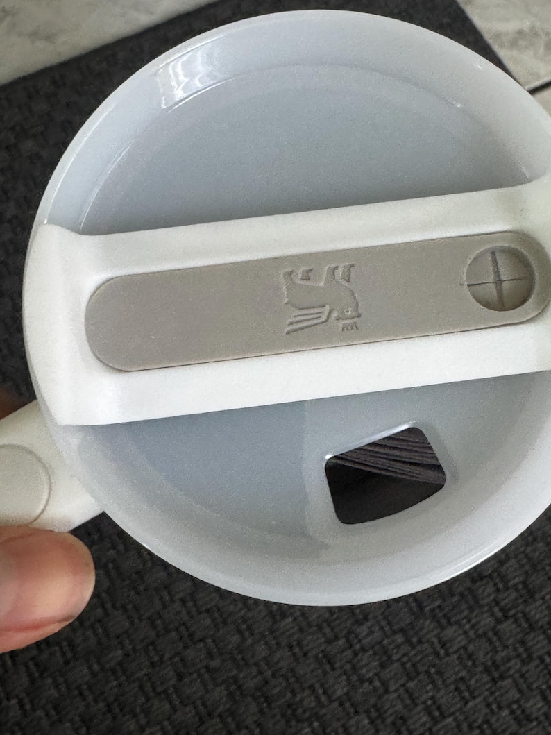 Puede incluir: Tapa de taza de viaje blanca y gris con un acento gris con un logotipo de p&aacute;jaro. La tapa tiene un cierre deslizante y una peque&ntilde;a abertura para beber. La tapa de la taza es de pl&aacute;stico.