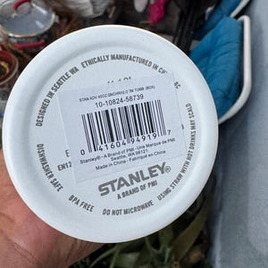 Puede incluir: Tapa blanca de vaso Stanley con c&oacute;digo de barras e informaci&oacute;n del producto. La tapa est&aacute; etiquetada como "Apto para lavavajillas" y "Sin BPA". El texto incluye "Dise&ntilde;ado en Seattle WA" y "No microondas".