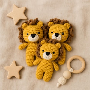 Puede incluir: Tres leones de crochet amarillos con melenas marrones, ojos negros y hocicos blancos están dispuestos con dos juguetes de madera en forma de estrella y un mordedor de madera con un acento de cuentas color crema. Los artículos están sobre una superficie de tela beige.