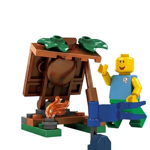 K&ouml;nnte beinhalten: Ein Kunststoff-Baustein-Set mit einer gelben Minifigur mit l&auml;chelndem Gesicht, die ein blaues T-Shirt mit einem rosa R-Logo und eine gr&uuml;ne Hose tr&auml;gt. Das Set enth&auml;lt eine braune Struktur in Holzoptik mit gr&uuml;nen Bl&auml;ttern und einer kleinen orangefarbenen Flamme.
