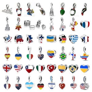 May include: A collection of silver-toned metal charms featuring various designs including national flags, landmarks, maps, and symbols. The charms are shaped as hearts, stars, and icons, with colorful enamel details representing different countries and cultures.