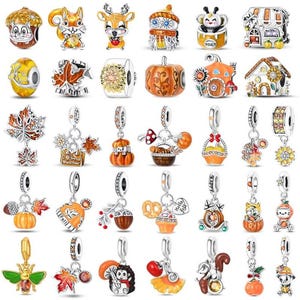 Könnte beinhalten: Eine Sammlung von dreißig Metallanhängern mit herbstlichen Motiven wie Eichhörnchen, Kürbissen, Eicheln, Sonnenblumen, Pilzen und Häusern. Die Anhänger sind in Orange-, Gelb-, Braun- und Silbertönen gehalten und mit Emaille-Details verziert.