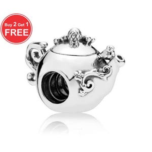 Könnte beinhalten: Ein silberner Charm in Form einer Teekanne. Der Charm hat aufwendige Details, darunter ein ananasförmiger Knauf und florale Akzente. Der Charm hat ein großes Loch zum Auffädeln auf ein Armband. Das Bild enthält einen roten Kreis mit dem Text "Buy 2 Get 1 FREE".