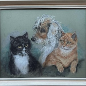 May include: A framed pastel artwork depicting a black and white cat, a tan and white dog, and an orange cat. The artwork is titled "Frick Mittens and Copper 1968". The frame is a light wood colour.