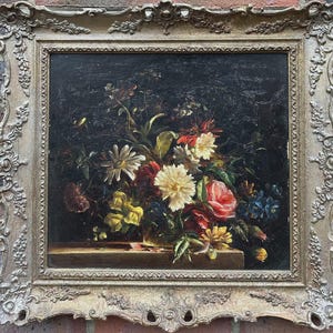 May include: An antique oil painting of a floral still life. The artwork features a bouquet of colorful flowers, including roses and dahlias, set against a dark background. The painting is in a decorative, ornate gold frame.