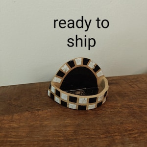 May include: A semi-circular ceramic wall pocket featuring a black and white checkered pattern along the outer rim. The interior is solid black, and the text "ready to ship" is printed in black letters above the object against a plain background.
