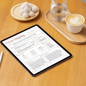 Może przedstawiać: Cyfrowy tablet wyświetlający arkusz roboczy "Verse Mapping", biały rysik, filiżankę latte, szklankę wody i talerz białych słodyczy na drewnianym stole. Arkusz roboczy zawiera tekst i linie na notatki.