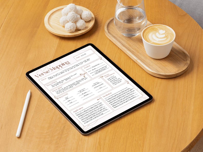 Może przedstawiać: Cyfrowy tablet wyświetlający arkusz roboczy "Verse Mapping", biały rysik, filiżankę latte, szklankę wody i talerz białych słodyczy na drewnianym stole. Arkusz roboczy zawiera tekst i linie na notatki.