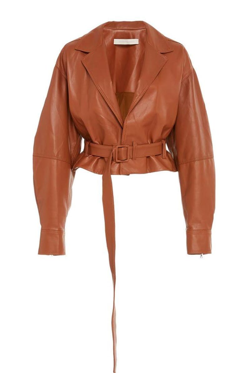 May include: A brown leather jacket with a belted waist and long sleeves. The jacket has a notched collar and a long belt that hangs down. The jacket is a medium brown color.