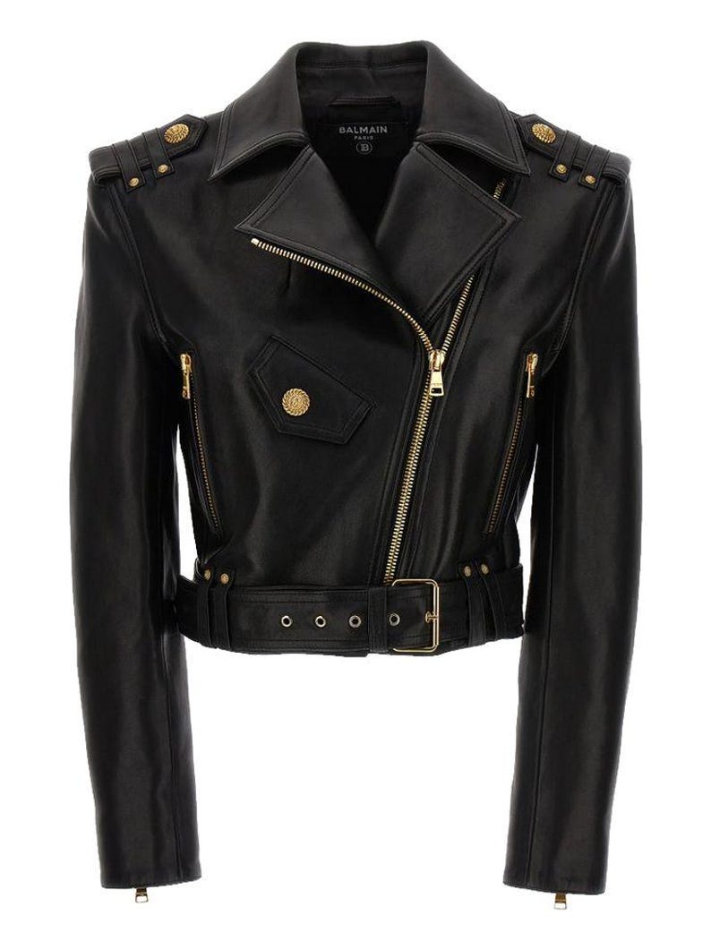 May include: Black leather jacket with a classic biker style. Features an asymmetrical zipper, a belted waist, and gold-tone hardware. The jacket has shoulder epaulets with decorative buttons and a small pocket.